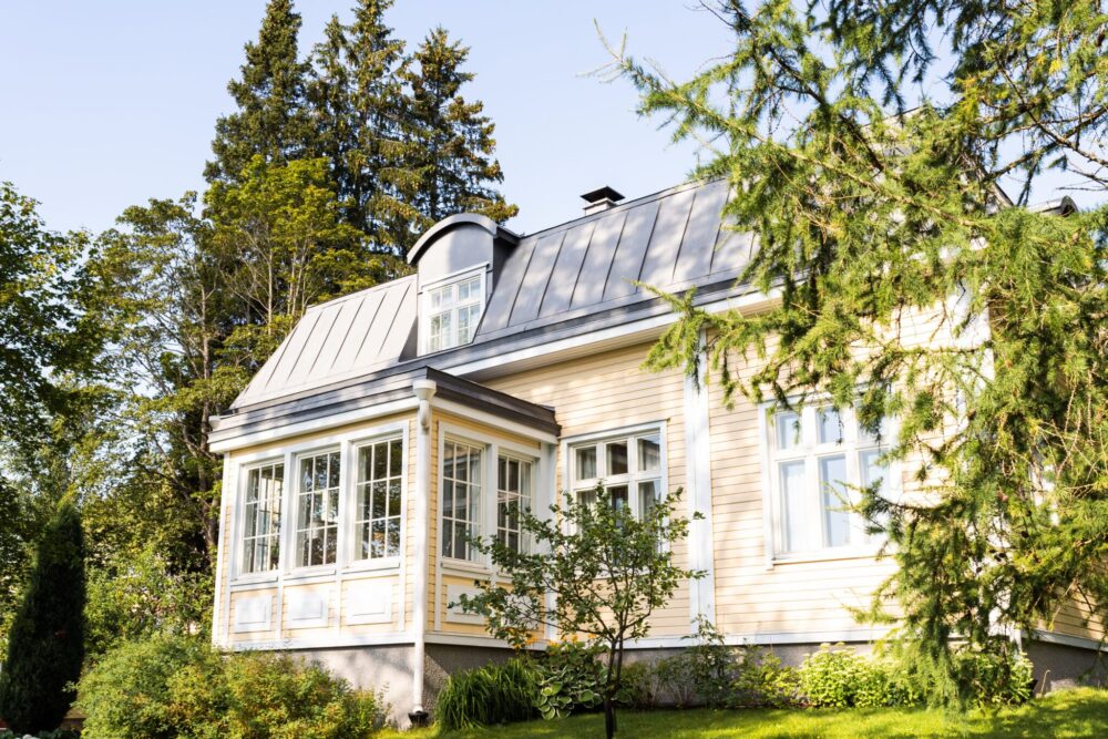 Keltainen talo juuri maalattuna metsän keskellä auringon valaisemana