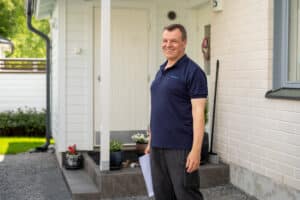 Mies seisoo asuntonta edustalla hymyille leveästi.