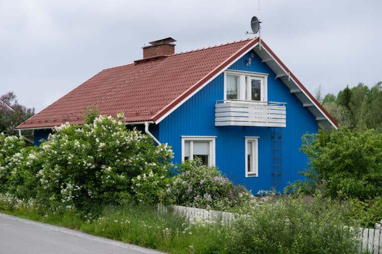 Juuri maalattu sininen omakotitalo rehevän puutarhan keskellä